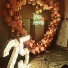 Yeh 25th anniversary ke liye rose gold aur pastel pink color mein heart shape balloon frame hai. Saath mein '25' number ke light letters bhi hain.