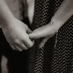A close-up, black and white shot focusing on the simple, powerful gesture of holding hands. This detailed shot tells a story of connection and tenderness.