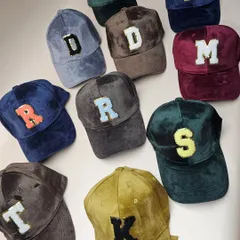 An overhead shot of our colorful collection of personalized suede caps, showing the different letter and color combinations available.