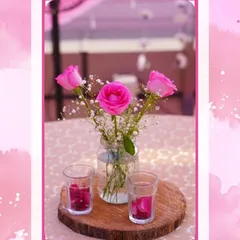 A simple yet beautiful centerpiece featuring pink roses in a mason jar on a rustic wood slice. This style of detailed decor is perfect for adding a personal and charming touch to tables at a more casual corporate gathering or team lunch.