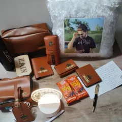 A full view of a personalized gift set, including a range of tan leatherette items like a passport cover, wallet, and pouches, plus a custom photo pillow.