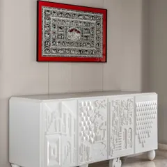 This image showcases a bespoke furniture piece we designed. The white sideboard features intricate, three-dimensional geometric patterns on its doors, turning a functional storage unit into a contemporary work of art.