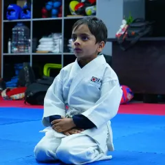 A young student kneels in the traditional seiza position, demonstrating the focus and discipline that is central to our karate training.