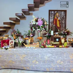 A stunning indoor buffet setup for a birthday party. The long table is laden with food and decorated with magnificent floral arrangements, creating a truly celebratory feel.