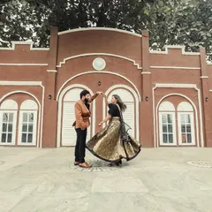 A beautiful twirling shot of a couple, with the bride's shimmering lehenga creating a stunning visual against a classic architectural backdrop.