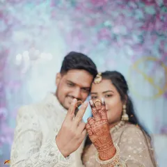 The couple proudly displays their engagement rings on their fingers, forming a 'V' for victory. The bride's intricate mehndi is beautifully visible in this joyful and symbolic photograph.