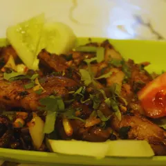 A close-up of our pork dry fry, garnished with fresh herbs. You can see the texture of the meat and the simple, fresh ingredients we use to make it.