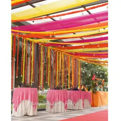 Ceiling decor can transform a space. For this Mehendi, I used vibrant drapes in yellow, pink, and orange, accented with hanging marigold garlands and bells, to create a festive canopy over the guest seating area.