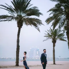 A dramatic portrait on the beach, with the Dubai skyline in the distance. The palm trees frame them perfectly, creating a sense of place and a touch of glamour.