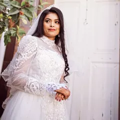 A beautiful portrait of our bride on her wedding day. This gown features a high neckline and intricate beading on the sleeves and bodice, creating a regal and elegant look.