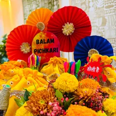 A beautiful display of my 'Balam Pichkari' Holi collection. The arrangement features bright dry fruit potlis, handcrafted paper pinwheels, and fresh marigolds, creating a perfect centerpiece for any Holi celebration.