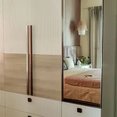 This bedroom showcases how to store in style. The floor-to-ceiling wardrobe features a mix of fluted and wood-grain finishes with rose gold handles, while the integrated mirror adds functionality and reflects light beautifully.