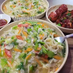 A hearty bowl of authentic chowmein, loaded with fresh vegetables and a light sauce. You can also see a side of chicken lollypop, making it a full meal.