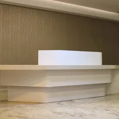 A frontal view of the bespoke reception desk, showcasing its clean lines and minimalist aesthetic. The combination of a solid surface top and layered base creates a piece of furniture that doubles as a work of art.