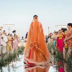 The bride's grand entrance down a mirrored aisle, her long veil trailing behind her. The guests' loving expressions and the stunning reflection create a powerful and emotional frame.