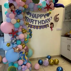 A mermaid-themed balloon arch for a 6th birthday, decorated with starfish, seahorses, and shell cutouts in a pastel color palette.