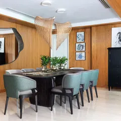 The formal dining room in the Magnolia project, featuring a stately dining table and chairs from our Koko collection. The space is illuminated by an artistic chandelier and reflected in a sculptural mirror, setting a tone of refined elegance.