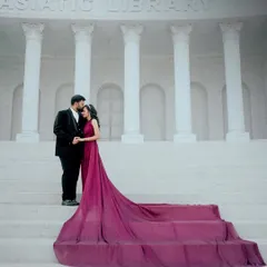 A timeless couple portrait on the steps of a classic colonial-style building. The long train of the gown cascading down the stairs creates a stunning visual for this pre-wedding photo.