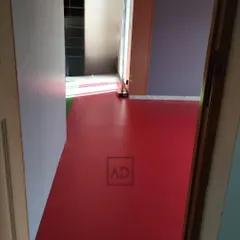 A view of the red sports flooring as it's being installed in a room. This seamless surface is easy to clean and maintains its color and performance over time.