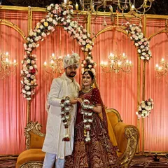 A picture-perfect moment on the wedding stage I designed. This setup features golden frames, dense floral decor, and multiple chandeliers against a soft pink drape, creating a classic and romantic setting.