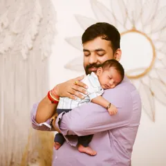A father's gentle embrace. This portrait captures the peaceful moment of a newborn sleeping soundly on their dad's shoulder.