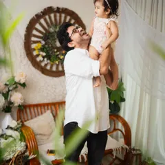 A father's joy as he lifts his daughter into the air. I often use creative framing, like shooting through foreground plants, to add an artistic and intimate feel to family photos.