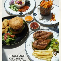 From our kitchen, with love. A top-down view of some of my savory favorites: a gourmet burger, a grilled panini sandwich, a hummus platter, and a side of fries.