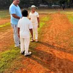 A coach provides personalized feedback to a young batsman on the pitch. This one on one instruction helps players understand and correct their technique in real-time.