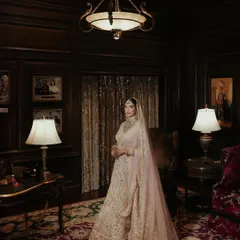 A full-length bridal portrait of Sanskriti within the dark, wood-paneled interiors of the Rambagh Palace, creating a dramatic and opulent mood.