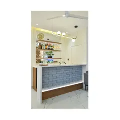 An indoor bar unit designed for clients who love to entertain in style. The design features a grey brick-textured front with under-lighting, a white marble top, and elegant shelving for glassware, creating a chic and functional entertainment hub.