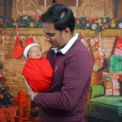 A proud father holds his sleeping newborn during their first Christmas photoshoot. These are the quiet, precious moments that become treasured family memories.