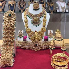 A complete South Indian bridal set, ready for a grand wedding. This gold-look alike set includes a Lakshmi choker, a long haram, matching jhumkas, a vaddanam (waist belt), vanki (armlets), and a full bridal hair accessory set (jadai).