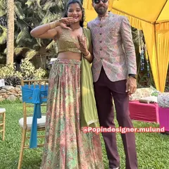 A happy couple at what looks like a mehendi or haldi function. The groom is wearing a stylish printed Jodhpuri-style jacket with maroon trousers, a great Indo-Western choice.