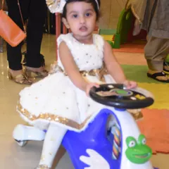 A happy toddler enjoying a ride on a colorful push car in the dedicated play zone. All my toys are clean, safe, and in great condition.