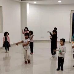 An instructor leads a group of young dancers through a new routine. Our classes are interactive, ensuring each child understands the steps and feels engaged.