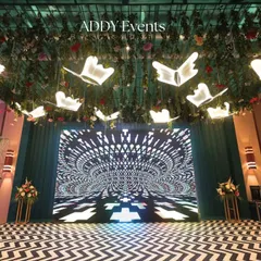 A modern stage design featuring a high-resolution LED screen with hypnotic visuals. The ceiling is adorned with illuminated butterfly-shaped fixtures, creating a unique and immersive environment for a tech conference or brand activation.