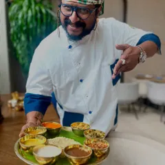 This is the heart of our celebration, a Sadya served on a traditional banana leaf. I am holding a platter filled with small bowls of curries, thoran, and pickles, each one a taste of Kerala's rich agrarian heritage and festive spirit. It's a wholesome experience I am proud to share.