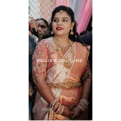 A candid moment of our bride in her custom peach-toned wedding outfit. The sheer sleeves of the blouse are intricately embroidered, adding a delicate touch to her Kanchipuram silk saree.