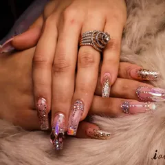 A close-up of a full set of custom jeweled nail extensions. This look combines glitter, iridescent crystals, and a flawless shape to create a truly luxurious and eye-catching manicure perfect for weddings or celebrations.
