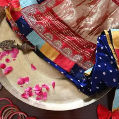 Preparing the saree for its new home. The rich colors of the patchwork, the shimmer of the Zardozi, and the deep blue of the Bandhni silk are laid out, ready to be worn and cherished.