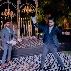 The stage is set for a performance. This Sangeet features a modern black and white patterned dance floor, a backdrop of candle-like lights, and elegant chandeliers, creating a sophisticated and energetic space.