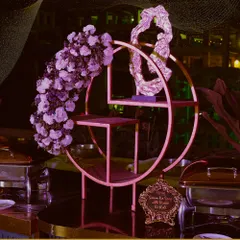 Artistry in every detail. This unique circular display stand, adorned with a cascade of purple flowers, serves as a stunning focal point for our dessert or appetizer presentations.