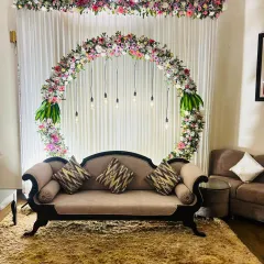 We can transform any corner of your home into an elegant space for an engagement or small party. This setup features a circular floral arch with mixed fresh flowers and hanging Edison bulbs, creating a modern and sophisticated backdrop for your special moments.