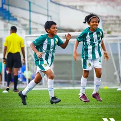 The joy and energy of youth football. Two young players celebrate a moment in the game with pure, uncontainable excitement.