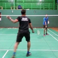 Here, a player practices their swing form with guidance from a coach. Correcting technique early is fundamental to developing powerful and accurate shots in badminton training.