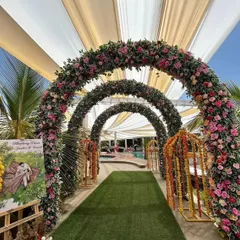 A beautiful floral archway tunnel for a daytime event. The series of arches covered in pink and green flowers creates a stunning photo opportunity and a memorable entrance.