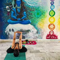 Practicing Supta Virasana (Reclining Hero Pose) in Rishikesh, in front of a beautiful mural of Lord Shiva and the chakras. The energy of this holy city is truly special.