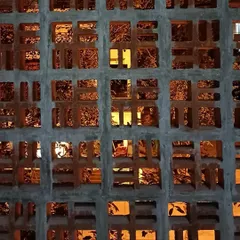 A close-up of the custom-designed breeze block jali wall during construction. The warm interior light filtering through the pattern shows how this feature works to create visual interest and texture.