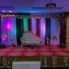 A versatile stage setup in a banquet hall with a multi-colored lighting system. The backdrop of drapes and fairy lights can be customized with different colors to match your event's theme.