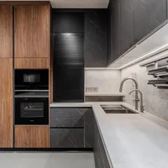 Warm contrast takes center stage in this Ahmedabad kitchen. Deep walnut wood meets the quiet drama of matte black fronts, while a seamless quartz counter and backsplash create a monolithic sweep.